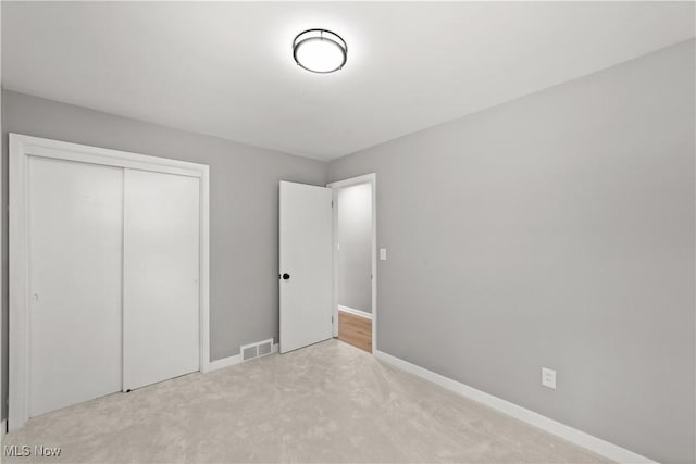 unfurnished bedroom featuring light carpet and a closet