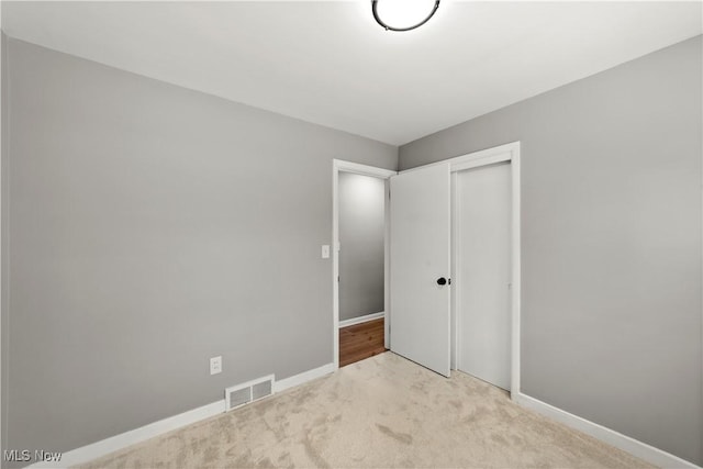 unfurnished bedroom with light carpet and a closet