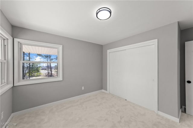 unfurnished bedroom with light colored carpet and a closet