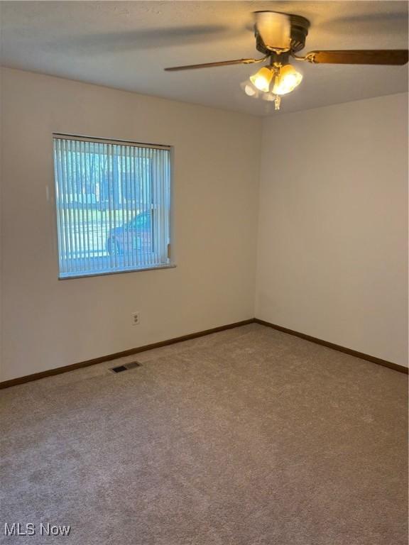 spare room featuring carpet floors and ceiling fan