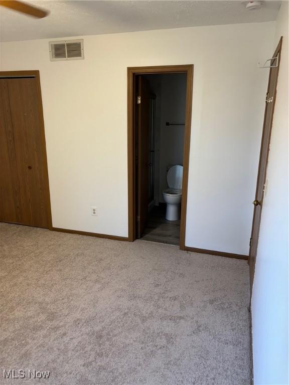 unfurnished bedroom with connected bathroom and light colored carpet