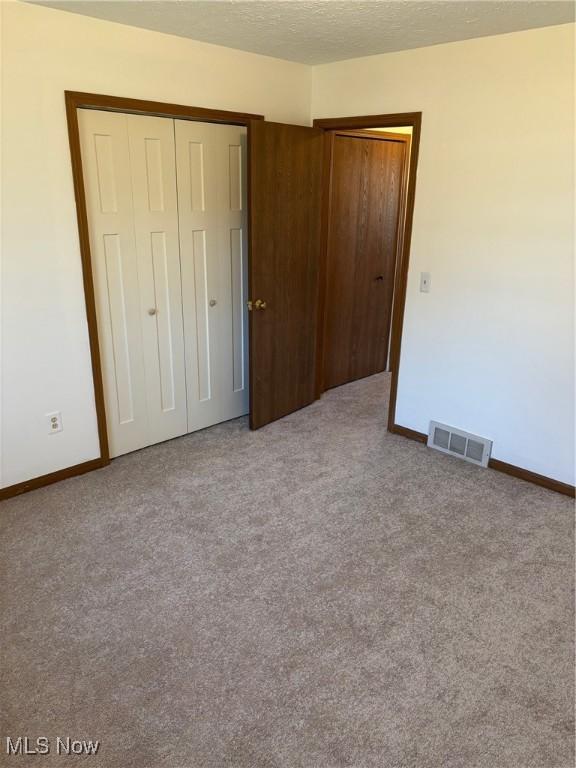 unfurnished bedroom with light colored carpet and a textured ceiling