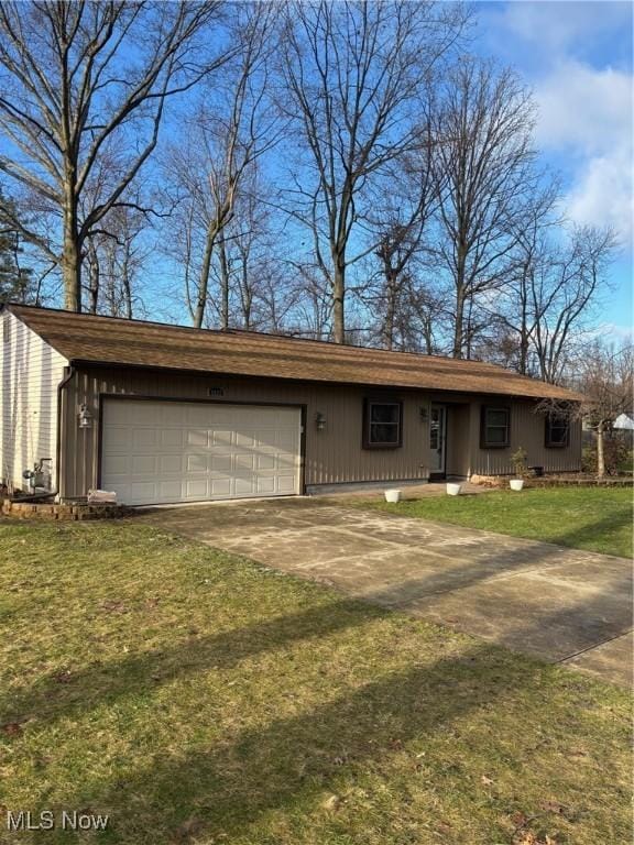 view of front of house featuring a garage, concrete driveway, and a front lawn