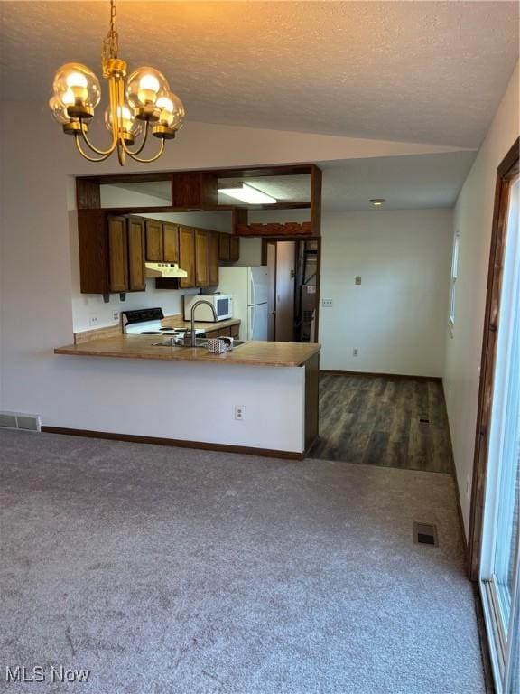 kitchen with dark colored carpet, lofted ceiling, decorative light fixtures, and kitchen peninsula