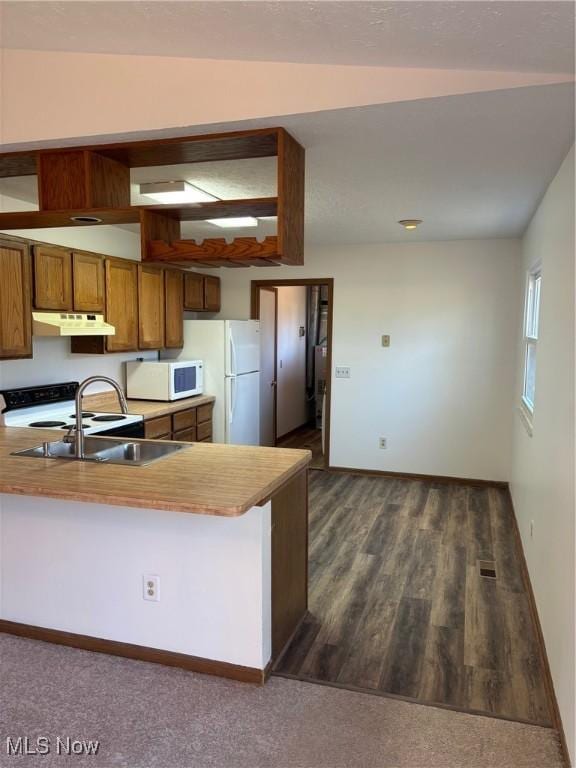 kitchen featuring sink, white appliances, dark wood-type flooring, and kitchen peninsula