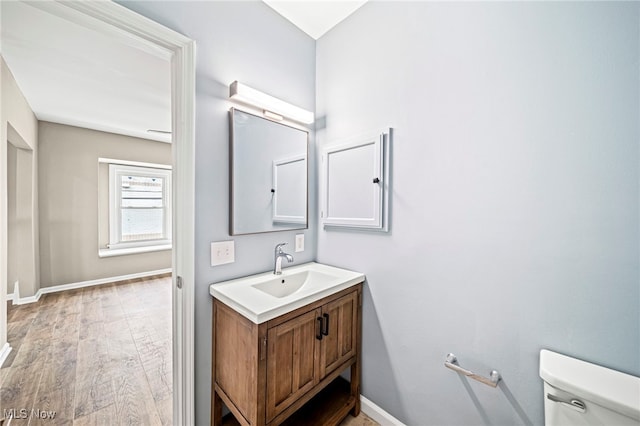 bathroom with wood-type flooring, toilet, and vanity