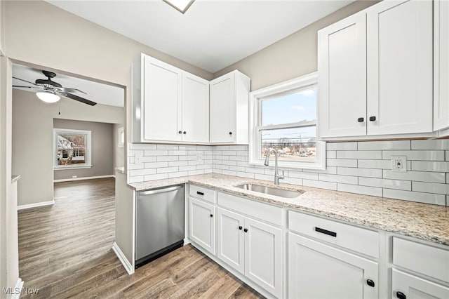 kitchen with sink, tasteful backsplash, stainless steel dishwasher, light hardwood / wood-style floors, and white cabinets