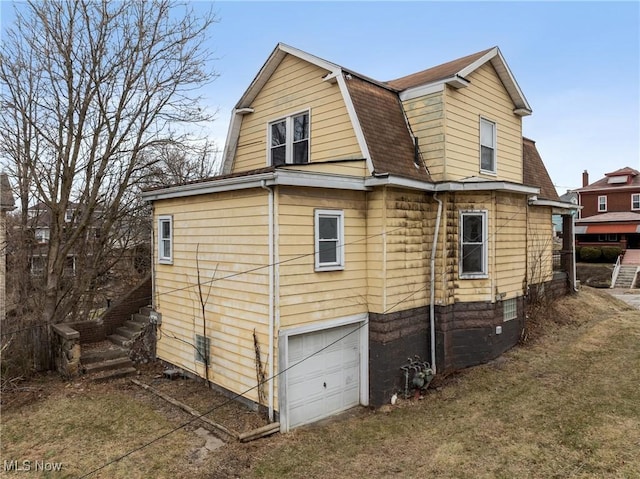 rear view of property featuring a garage and a lawn