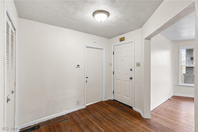 foyer entrance with dark hardwood / wood-style flooring and a textured ceiling