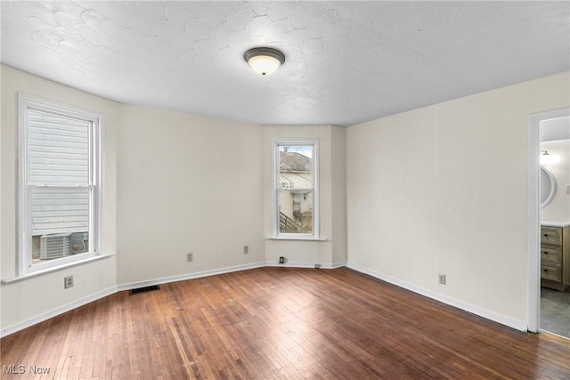 unfurnished room with dark wood-type flooring and a textured ceiling