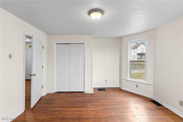 unfurnished bedroom featuring dark wood-type flooring and a closet