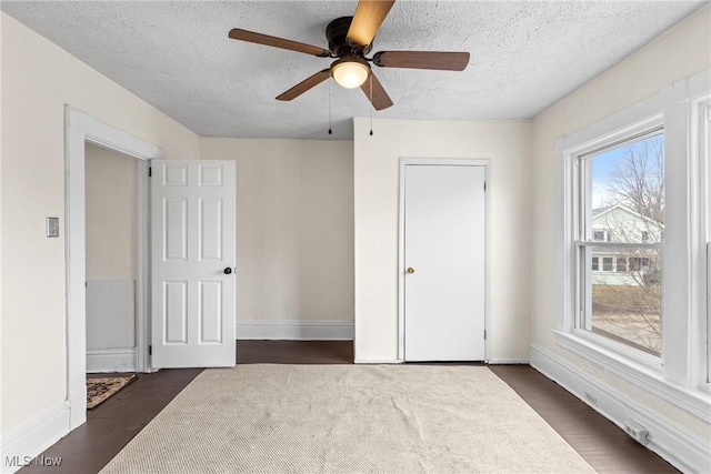 unfurnished bedroom with ceiling fan, dark wood-type flooring, and a textured ceiling