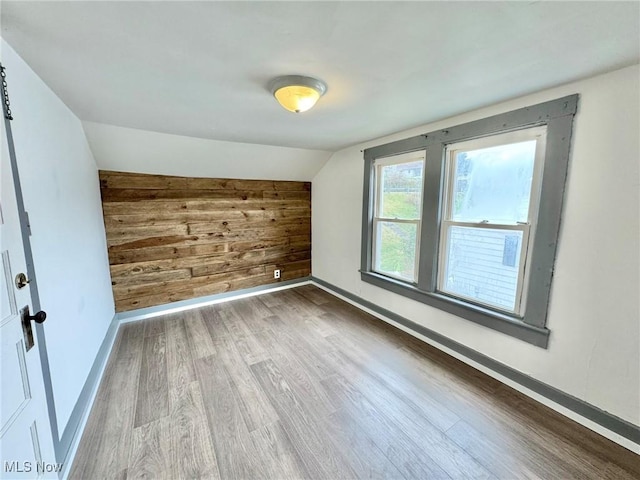 additional living space featuring lofted ceiling, hardwood / wood-style floors, and wood walls