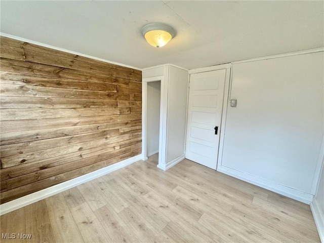 unfurnished room featuring wooden walls and light hardwood / wood-style floors
