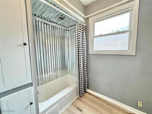 bathroom with wood-type flooring and shower / bath combo with shower curtain
