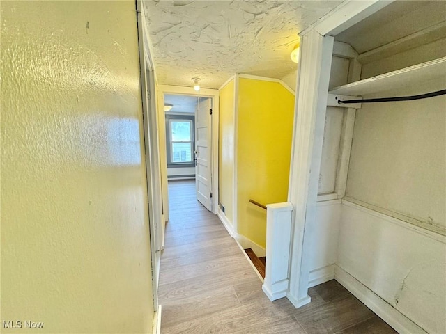 hallway featuring lofted ceiling, a textured ceiling, and light hardwood / wood-style floors