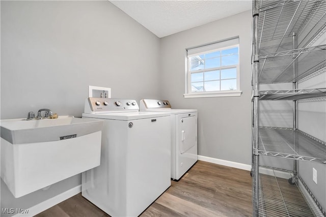 washroom with sink, hardwood / wood-style floors, a textured ceiling, and washer and clothes dryer