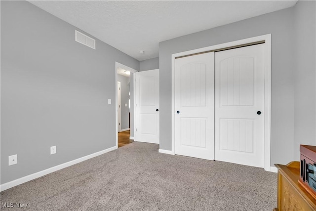 unfurnished bedroom with a closet, carpet, and a textured ceiling