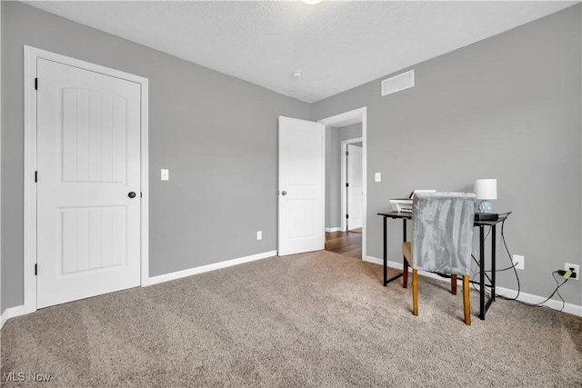 carpeted home office featuring a textured ceiling