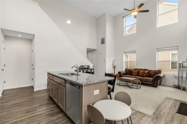 kitchen featuring sink, a kitchen bar, a kitchen island with sink, stainless steel dishwasher, and light stone countertops