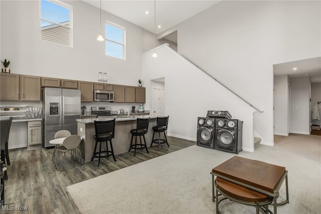 kitchen featuring a breakfast bar, appliances with stainless steel finishes, a center island, light stone counters, and decorative light fixtures