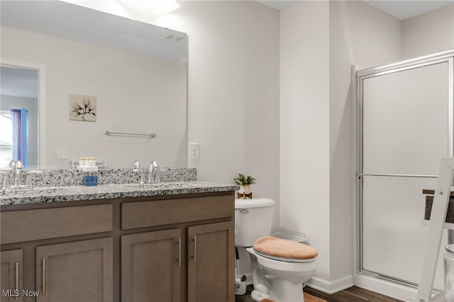 bathroom with hardwood / wood-style flooring, vanity, toilet, and a shower with door