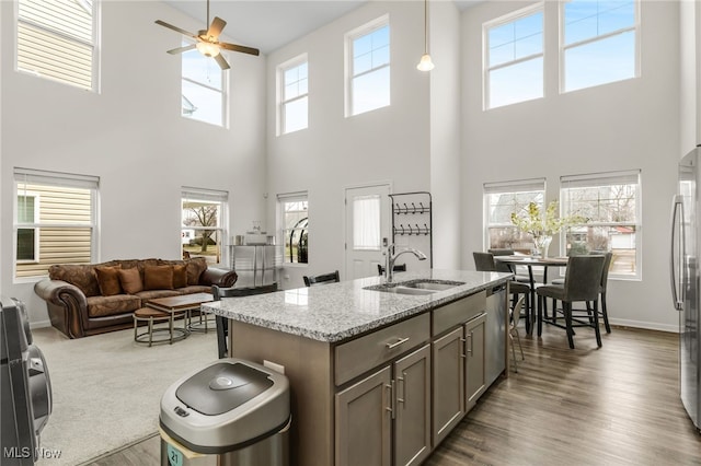 kitchen featuring sink, hanging light fixtures, appliances with stainless steel finishes, hardwood / wood-style flooring, and light stone countertops