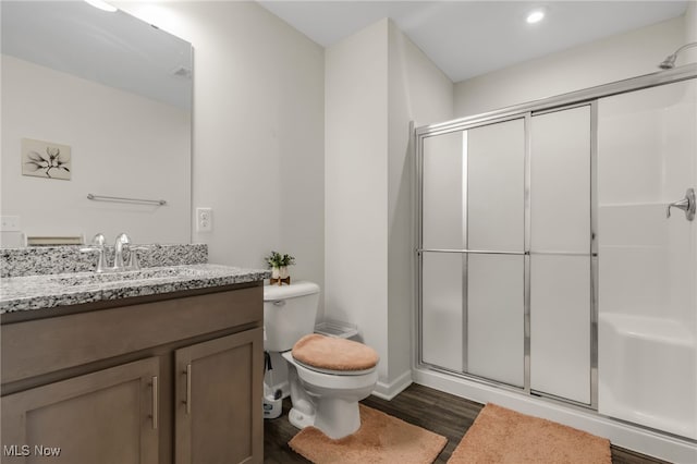 bathroom featuring walk in shower, vanity, toilet, and wood-type flooring