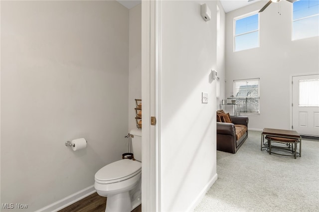 bathroom featuring ceiling fan, a towering ceiling, and toilet