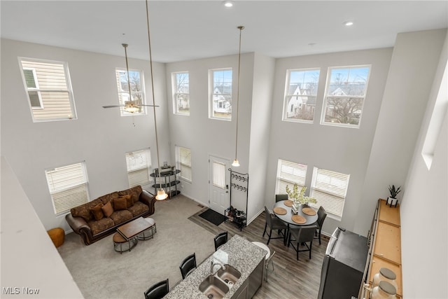 living room featuring sink, a towering ceiling, wood-type flooring, and ceiling fan