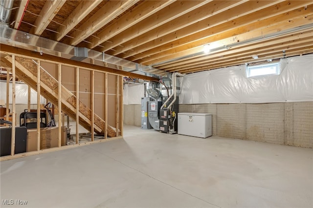 basement featuring heating unit, fridge, water heater, and brick wall