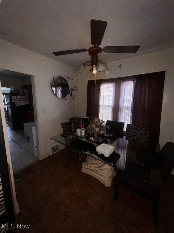 carpeted dining room with ceiling fan and a textured ceiling