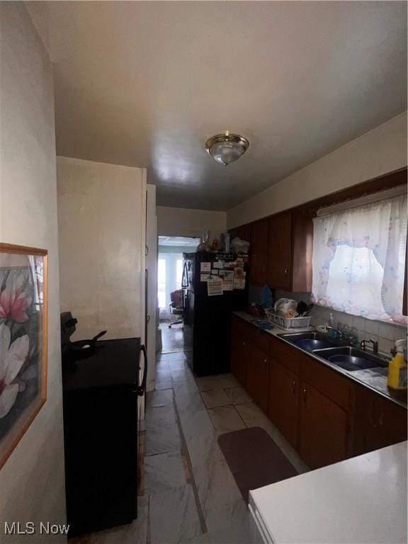 kitchen with tasteful backsplash, sink, range, and black fridge