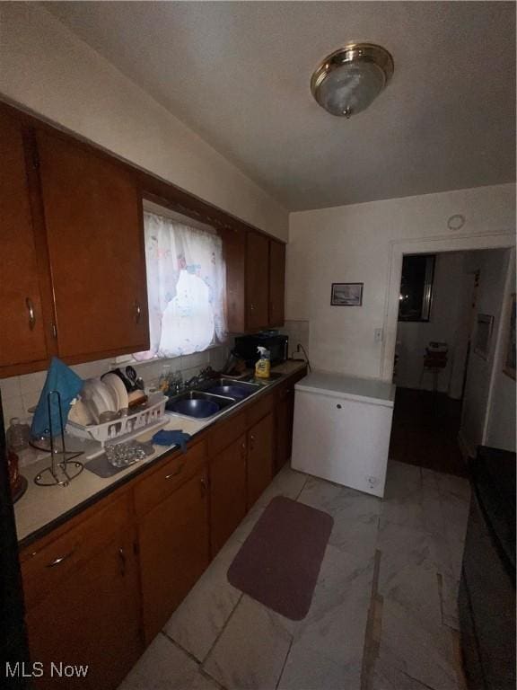 kitchen featuring sink, tile counters, and refrigerator