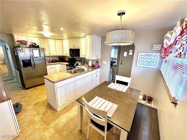 kitchen with sink, stainless steel fridge, kitchen peninsula, pendant lighting, and white cabinets