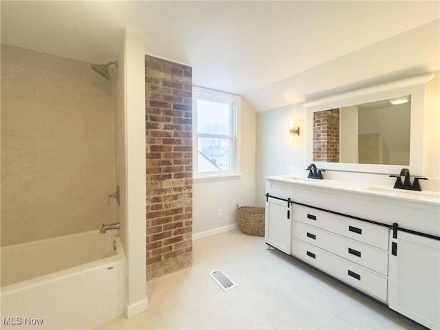 bathroom with lofted ceiling, vanity, and tiled shower / bath