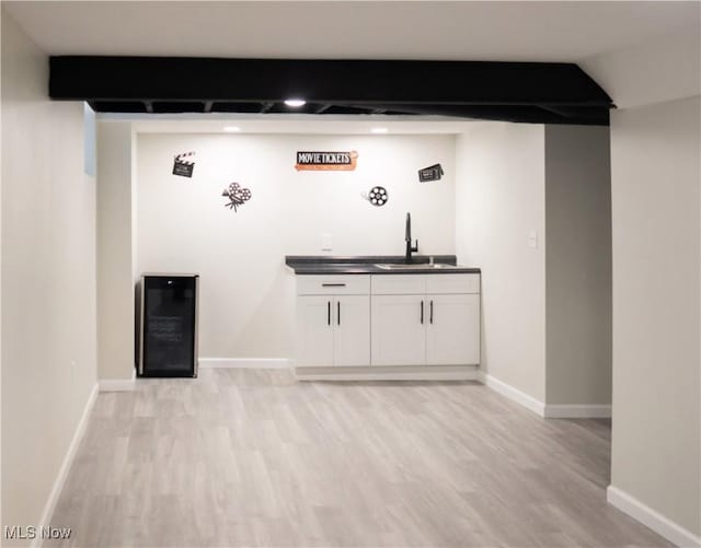 bar featuring sink, beam ceiling, white cabinetry, light hardwood / wood-style flooring, and beverage cooler