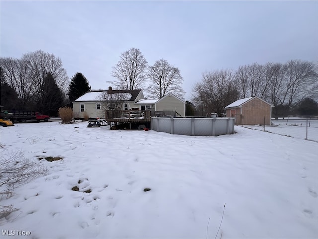 yard layered in snow with a swimming pool side deck