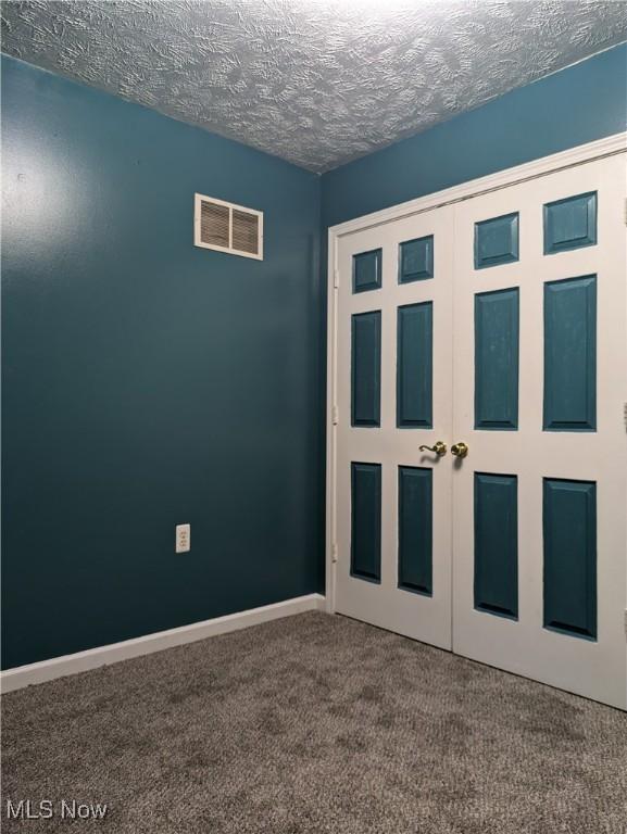 unfurnished bedroom with a closet, a textured ceiling, and carpet flooring