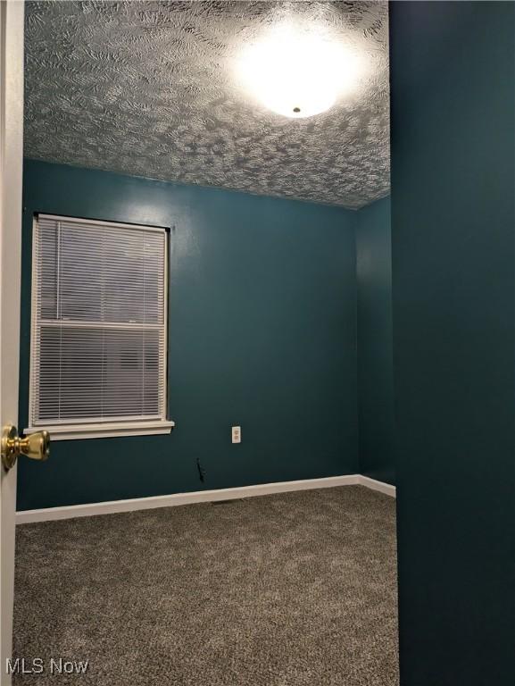 carpeted spare room with a textured ceiling