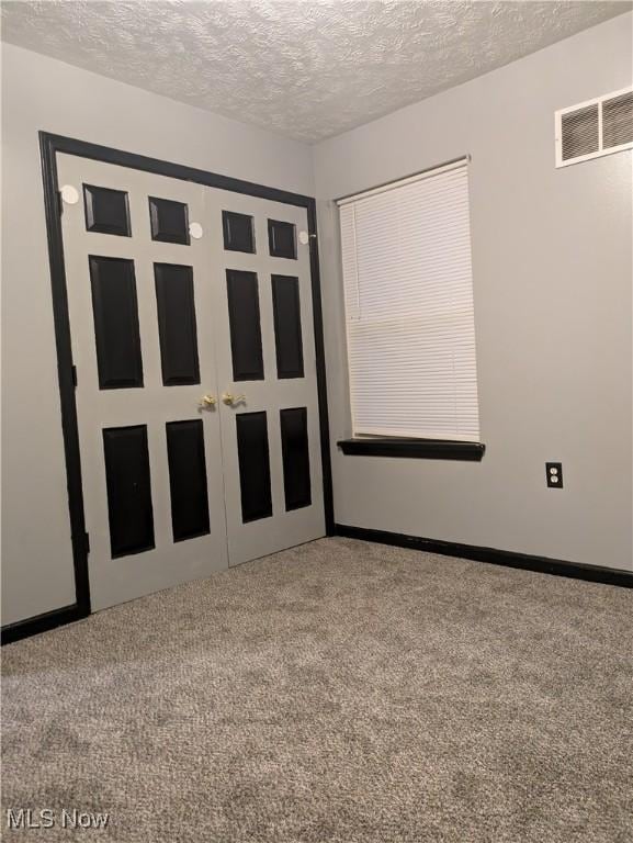 unfurnished bedroom featuring a closet, carpet, and a textured ceiling