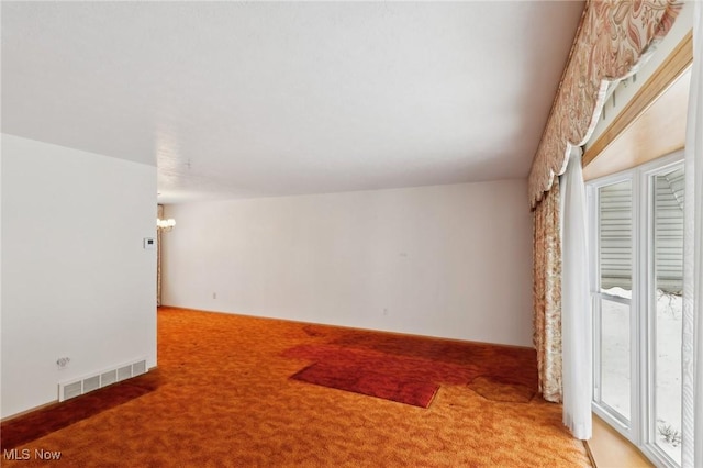 carpeted empty room with a chandelier