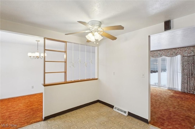 carpeted empty room featuring ceiling fan with notable chandelier and a textured ceiling