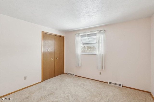 unfurnished bedroom with a closet, a textured ceiling, and carpet flooring