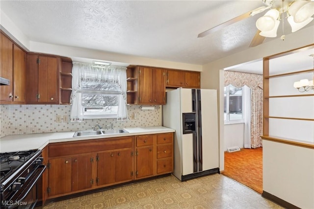 kitchen with tasteful backsplash, sink, black range with gas stovetop, white fridge with ice dispenser, and a textured ceiling