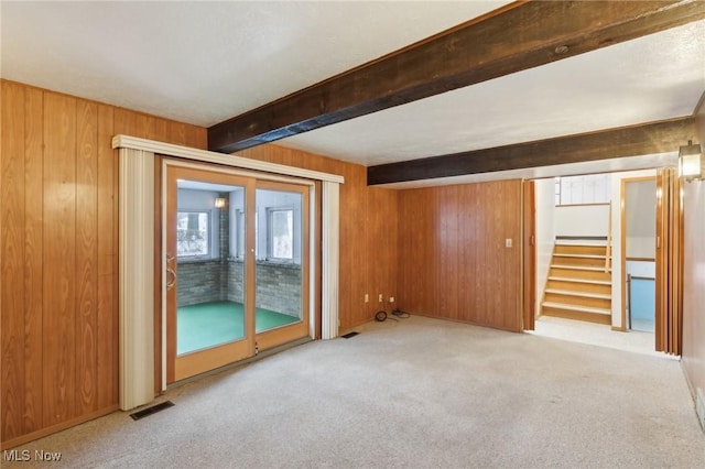 carpeted empty room with wooden walls and beamed ceiling