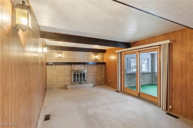 unfurnished living room featuring light carpet, a brick fireplace, beam ceiling, and wood walls