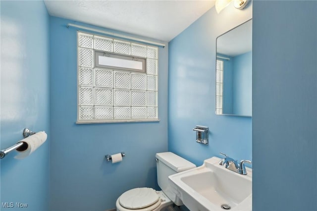 bathroom with plenty of natural light, toilet, and sink