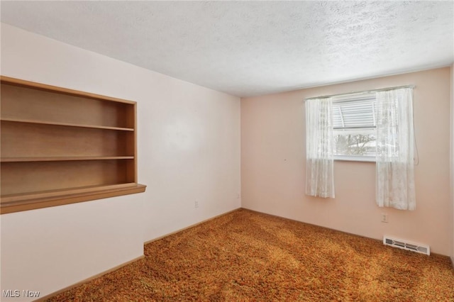 carpeted empty room featuring a textured ceiling