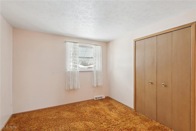 unfurnished bedroom featuring a closet, a textured ceiling, and carpet flooring